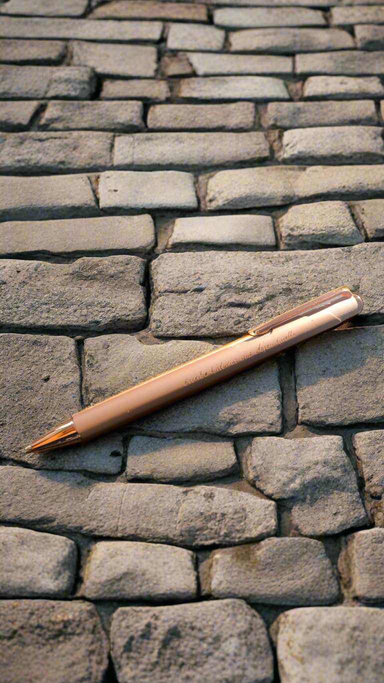Boli de metal color oro rosa con la frase "Escribe historias que dejen huella".