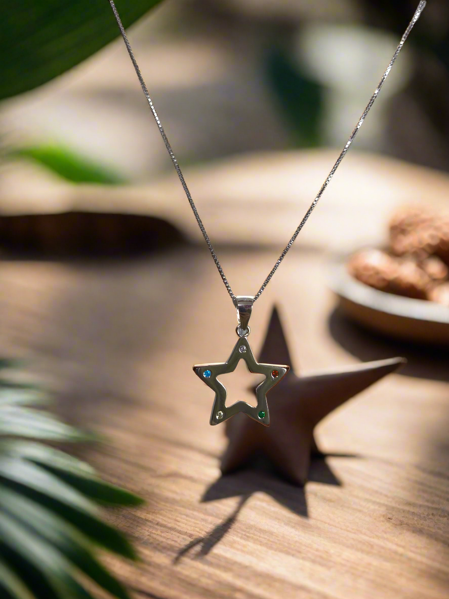 Colgante Nara con forma de estrella sobre mesa de madera en un fondo selvático en www.tuvinculoeterno.com