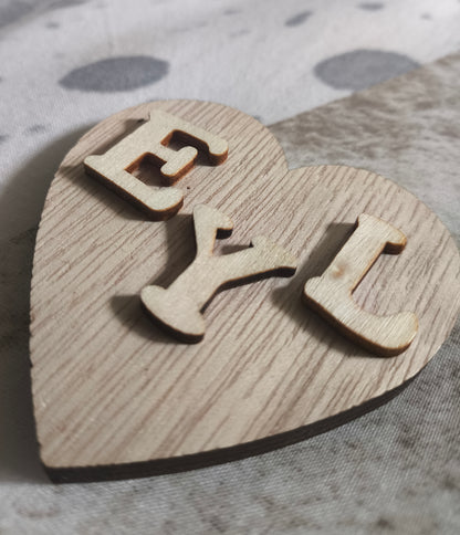 Corazón de madera con iniciales de los nombres de la pareja